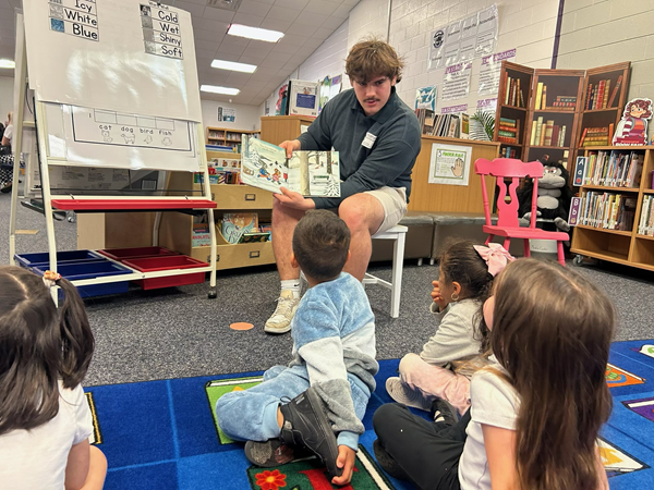 Teacher reading to kids sitting on mat Teacher reading to kids sitting on mat
