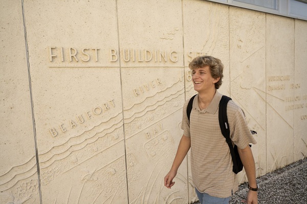 Student Walking by Map Wall