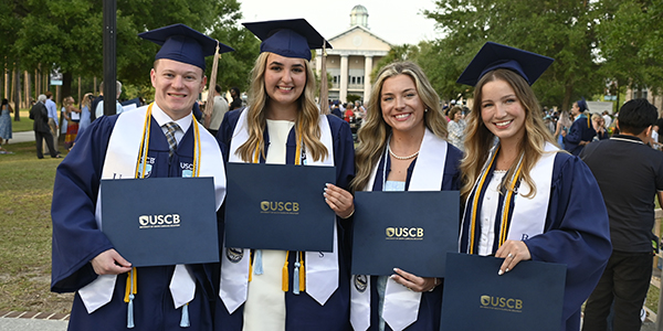 Four graduates in caps and gowns