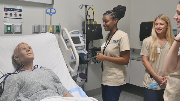Nursing students surrounding manikin