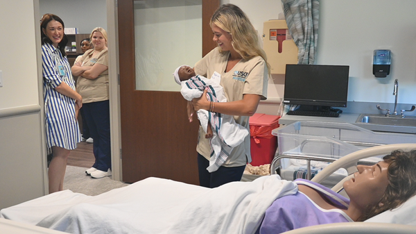 Nursing student holding manikin baby