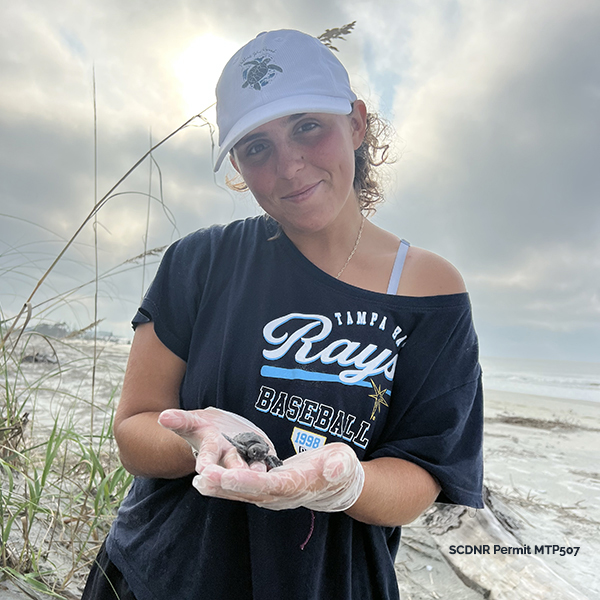 Young woman holding baby sea turtle