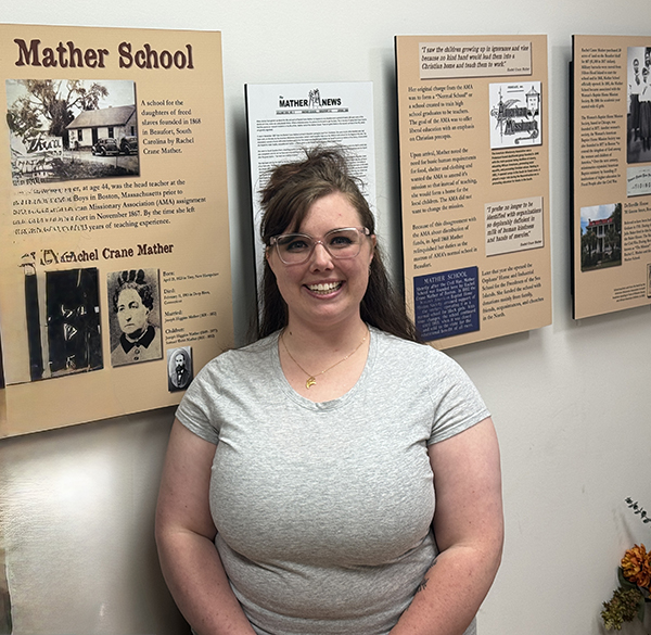 Voices of Mather student in front of poster