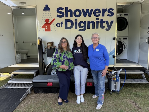 three people taking a selfie in front of a Showers of Dignity truck