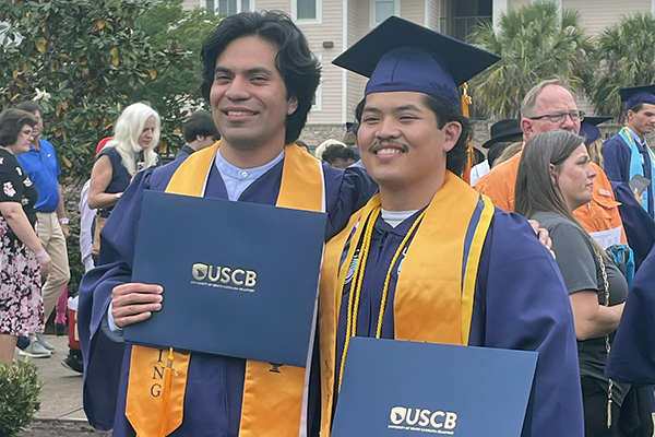 Two young men holding diplomas